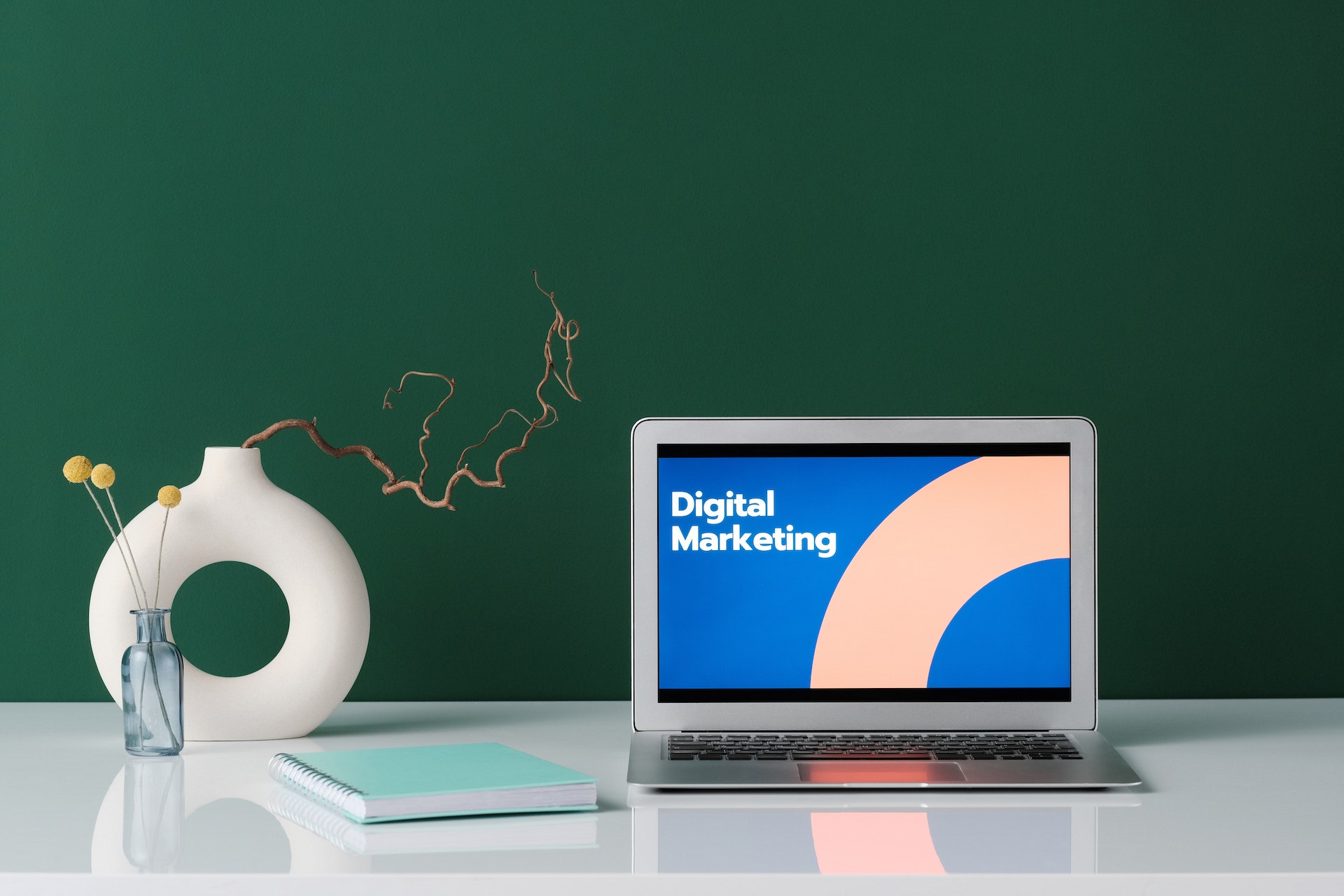 Como fazer consultoria de marketing digital: vasos, um caderno e um notebook cuja tela está escrito "digital marketing" sobre a mesa